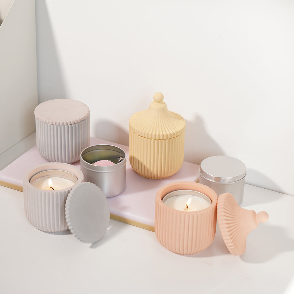 The yellow, gray, and pink candle jars with spine lids in the tray are the embodiment of handmade aesthetics.