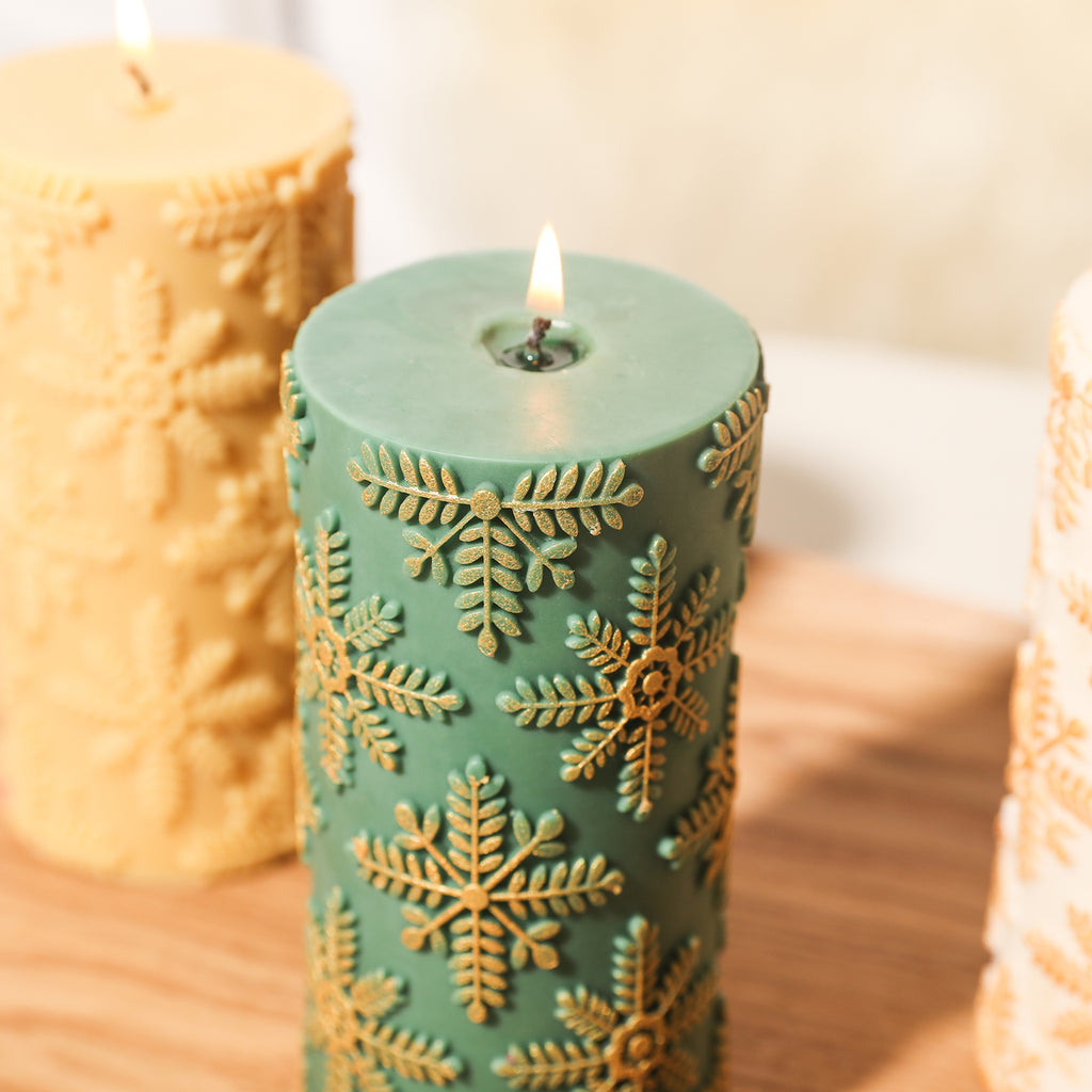 Close-up view of green long snowflake candle, with snowflakes coated with gold powder.