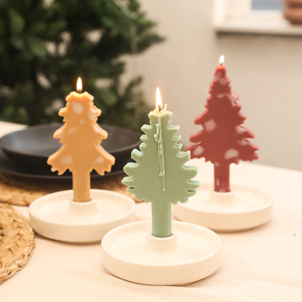 Three yellow, green, and red Christmas-shaped tapered candles lit on the table candle holder.