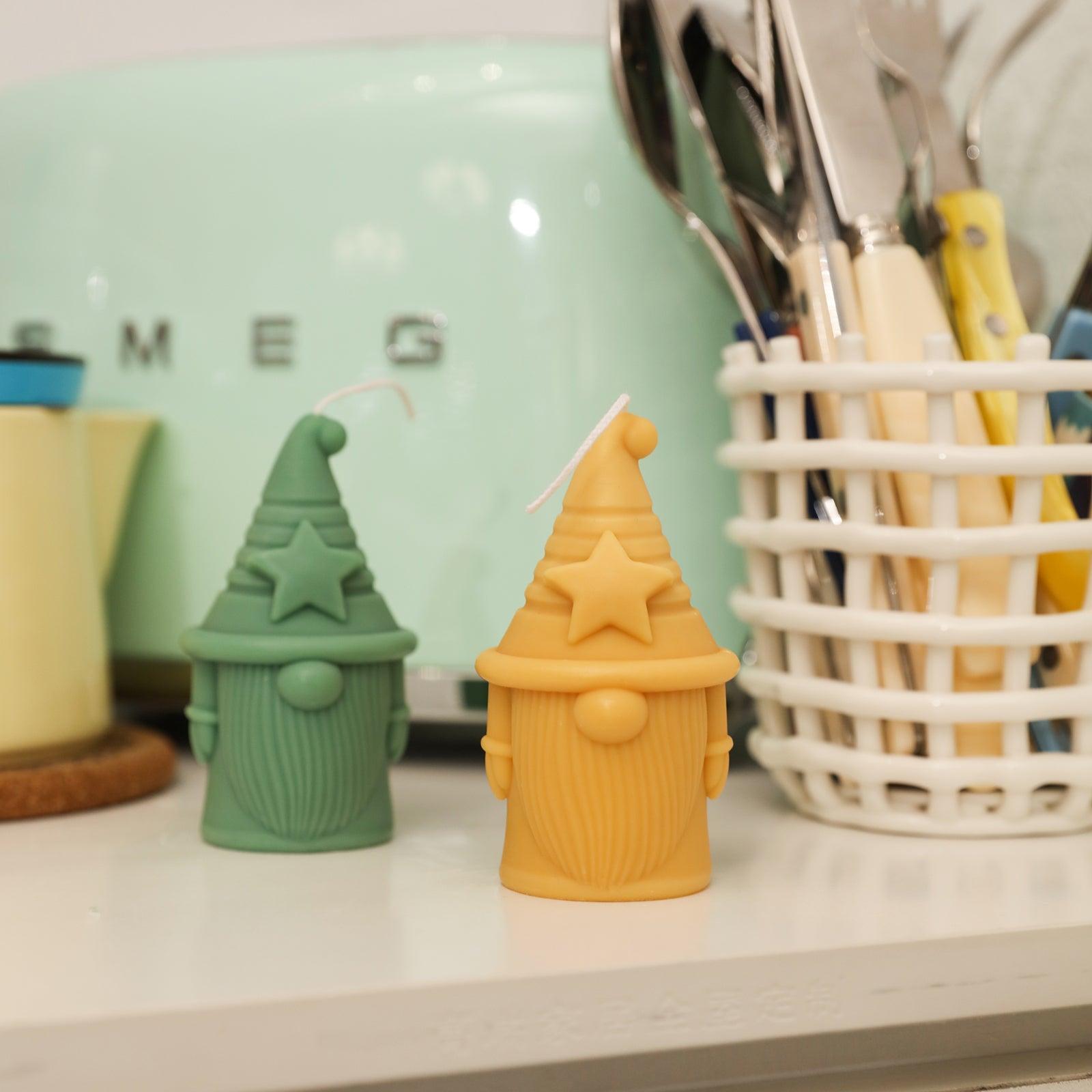 Yellow and green Stellan of Hat-tactic Gnome Squad Candle on tabletop - Boowan Nicole