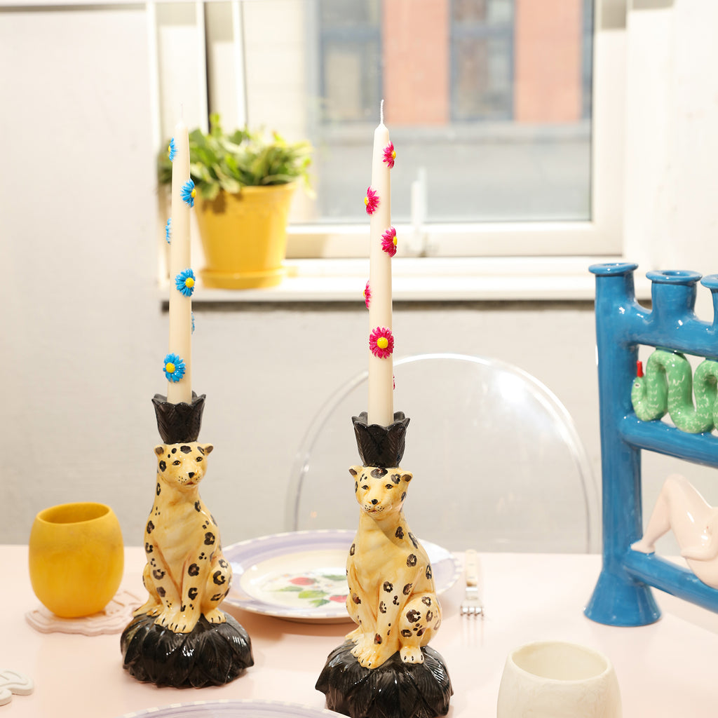 The leopard-shaped candle holders are placed with blue daisy and red daisy embossed taper candles, designed by Boowan Nicole.