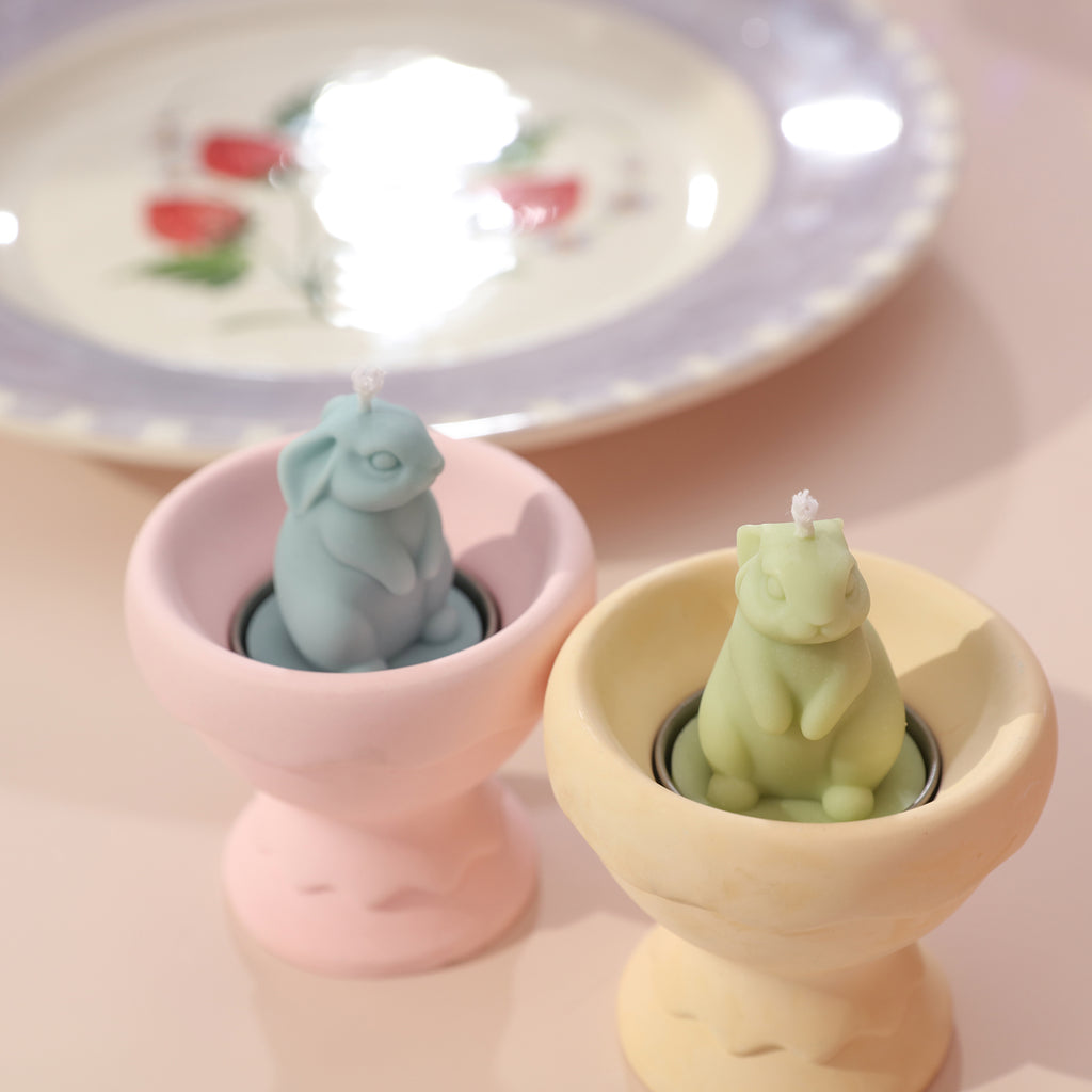 Two Easter bunny tealight candles displayed on an egg-shaped tealight candle holder.