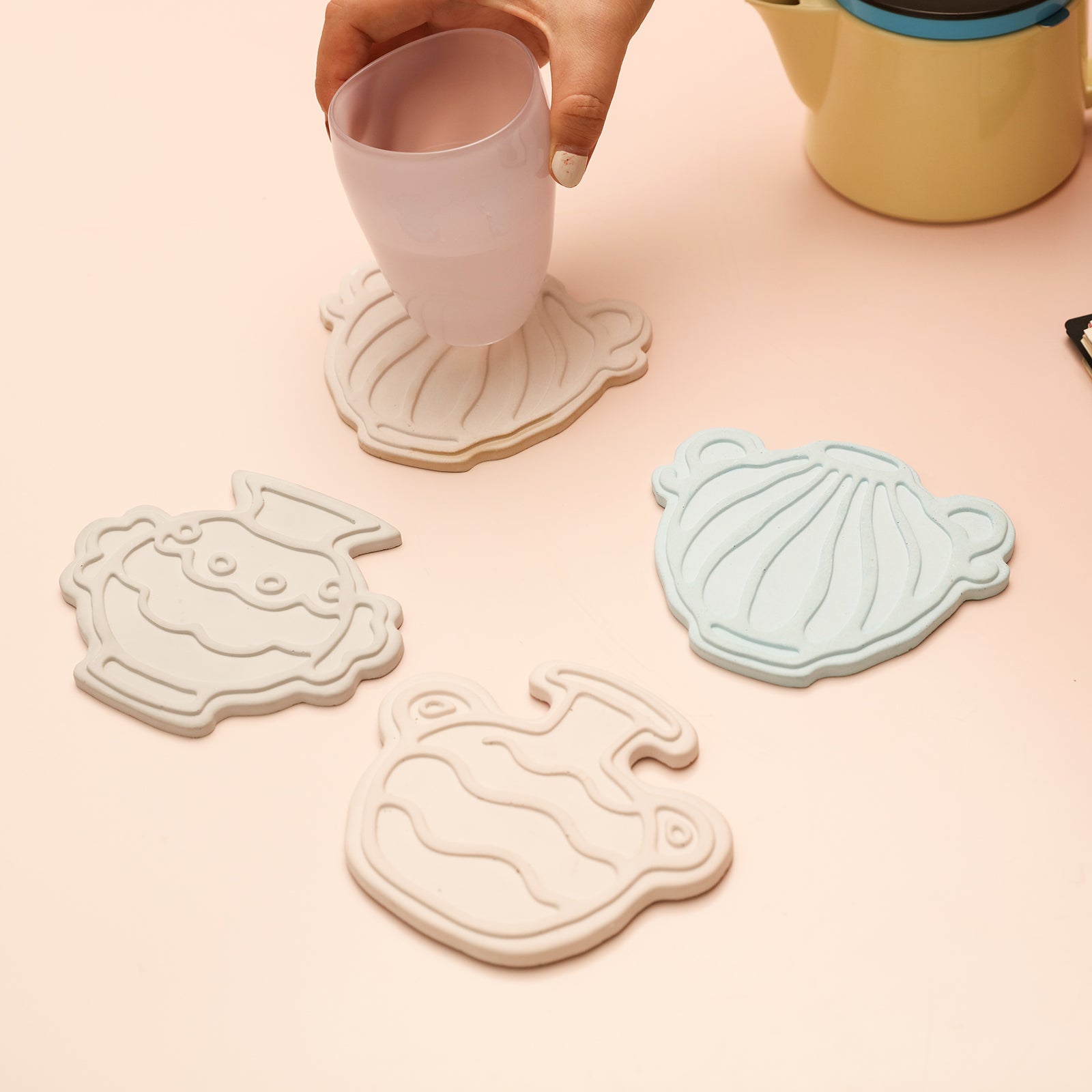 Classic kettle-shaped coasters are placed on the table, designed by Boowan Nicole.