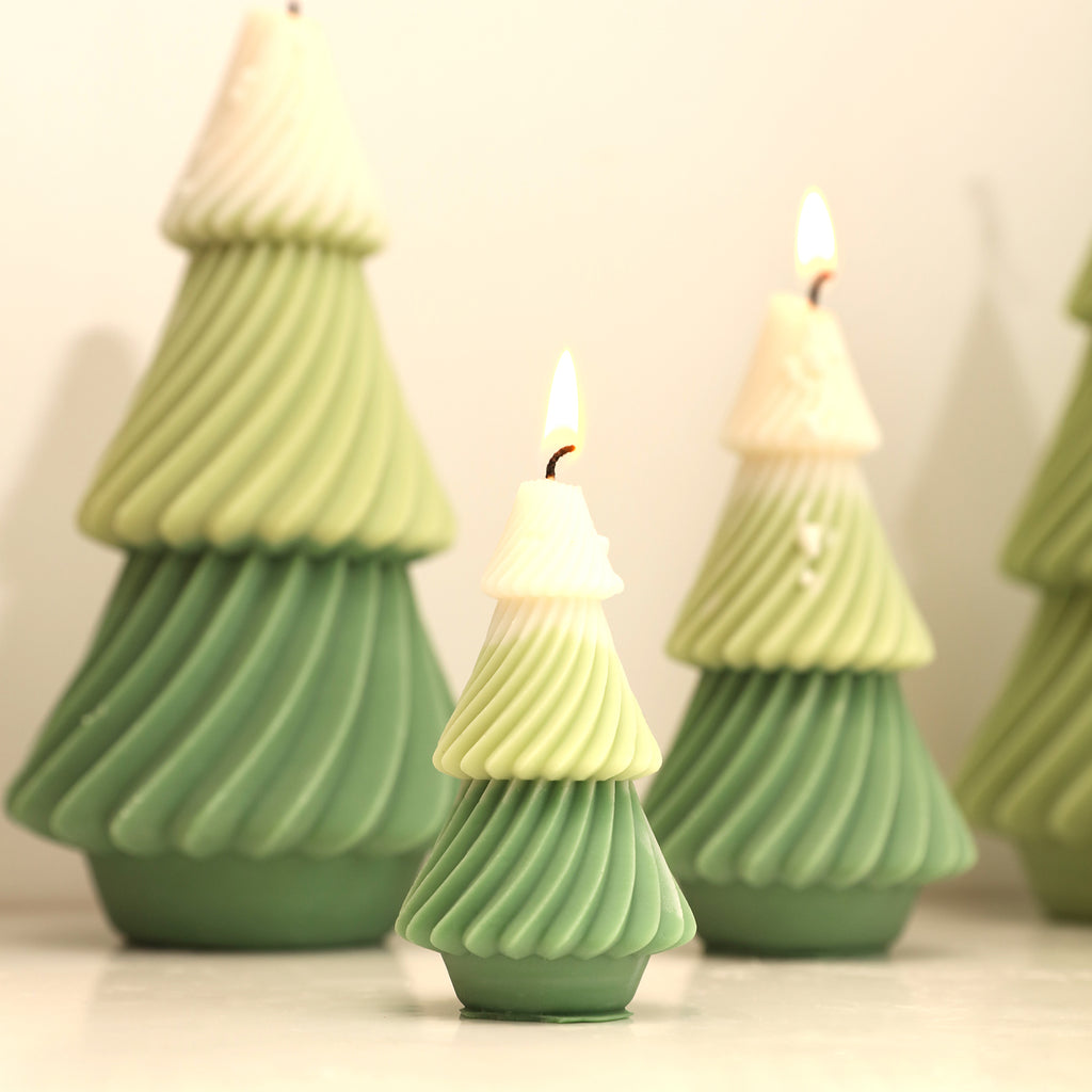 Small and medium green and white evergreen Christmas tree candles are burning slowly on the bookshelf - Boowan Nicole.