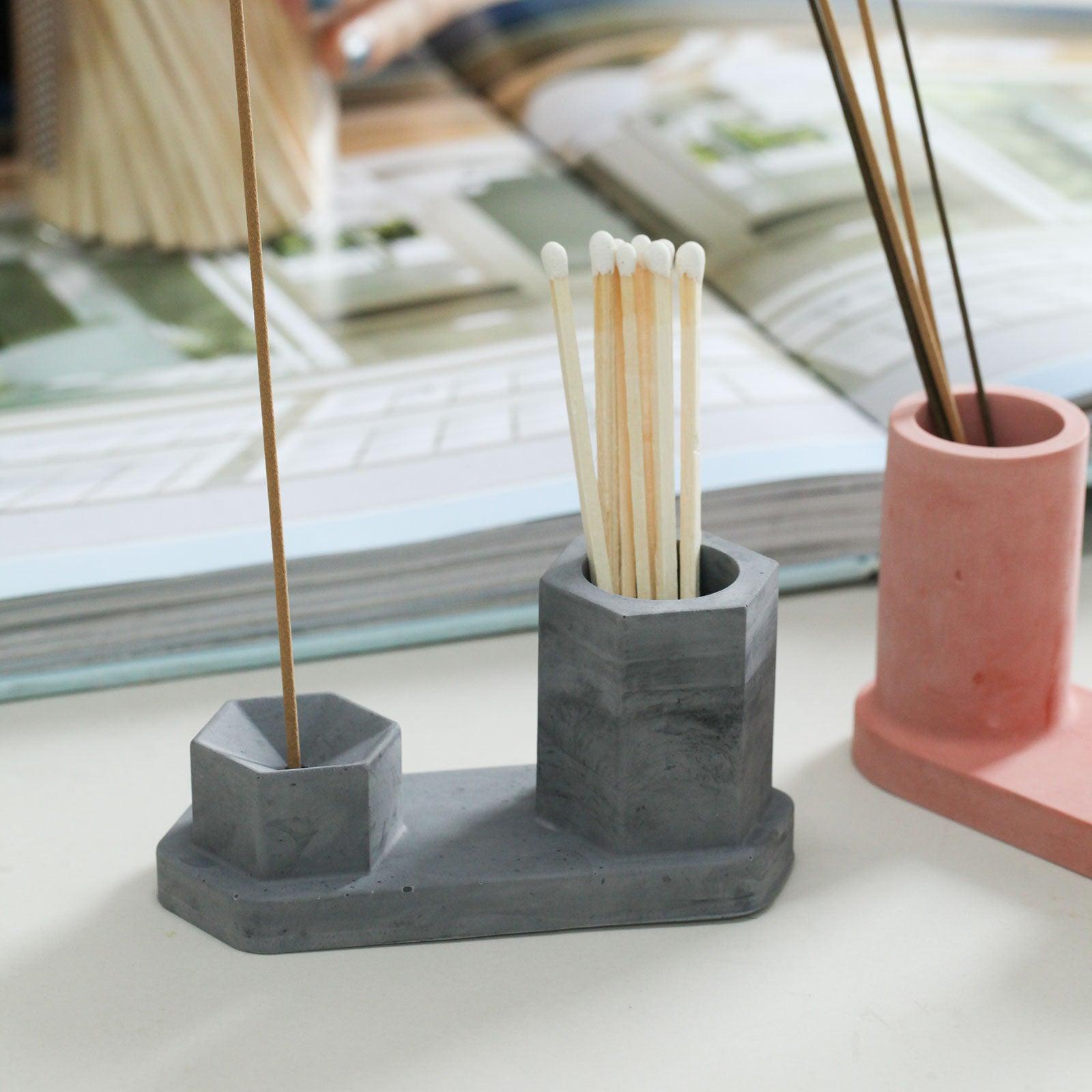 The cement-colored Hexagon Incense Holder holds an incense stick and a match on the other side-Boowan Nicole