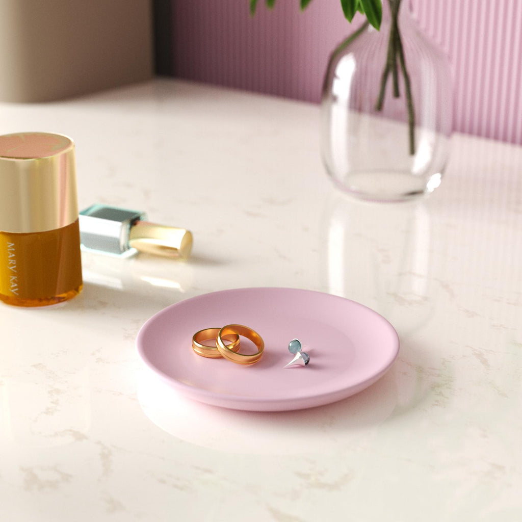 A pink round tray holding a pair of rings and earrings.