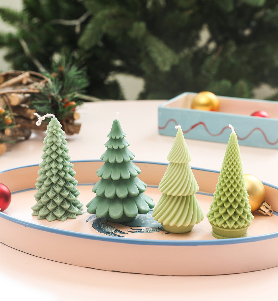 Four Christmas tree candles of different shapes placed on a tray.