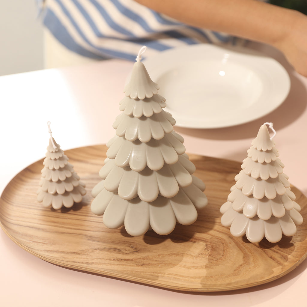 Off-white large, medium and small tiered Christmas tree candles in tabletop tray by Boowan Nicole.