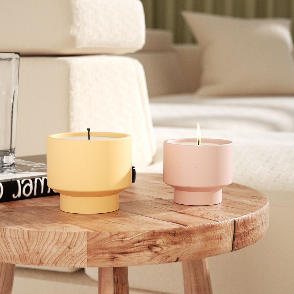 A large yellow bowl-shaped candle jar and a small pink candle jar being lit are placed on the coffee table