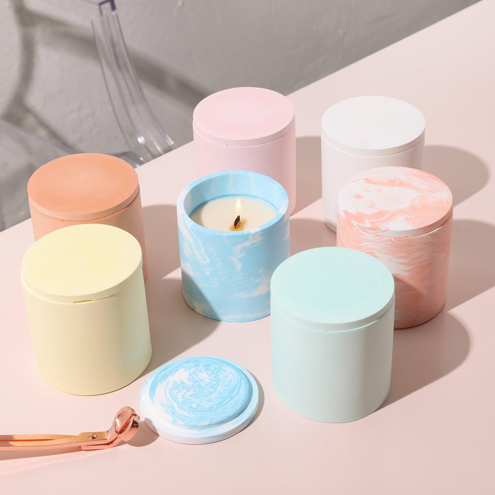 Seven candle jars, each in a different hue, adorn the table, accompanied by a pair of scissors for trimming wicks—a tableau of everyday beauty.