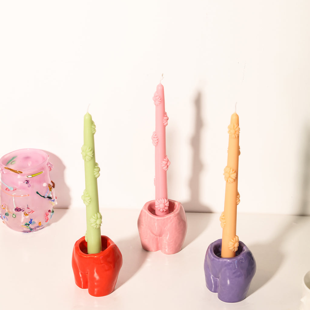 There are pink, green and yellow daisy embossed taper candles on the body model candle holders, designed by Boowan Nicole.