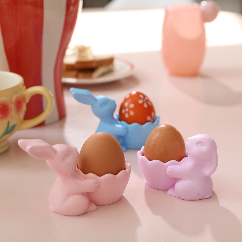 Three Easter Bunny egg cups with an egg placed in each
