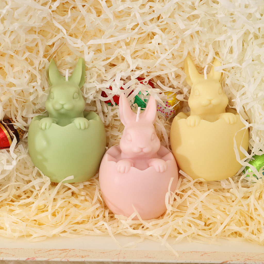 A gift box filled with green, yellow, and pink Easter candles, vibrant in color and full of holiday atmosphere.