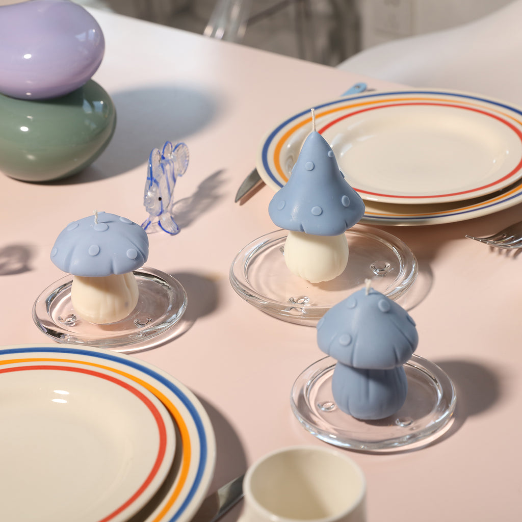 Mushroom-shaped candles with blue canopies are placed on the crystal tray of the dining table, designed by Boowan Nicole.