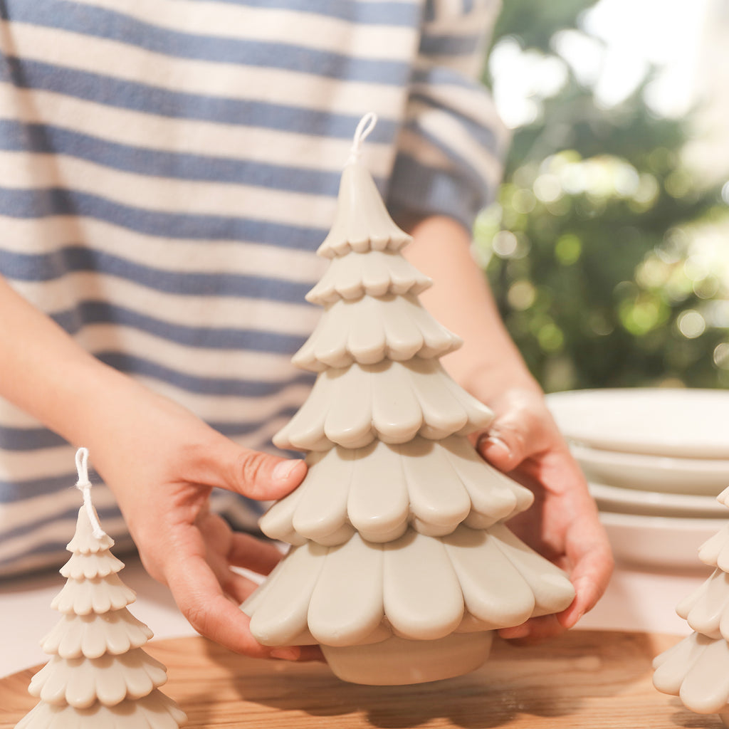 A large creamy white tiered Christmas tree candle is placed on the tray, designed by Boowan Nicole.