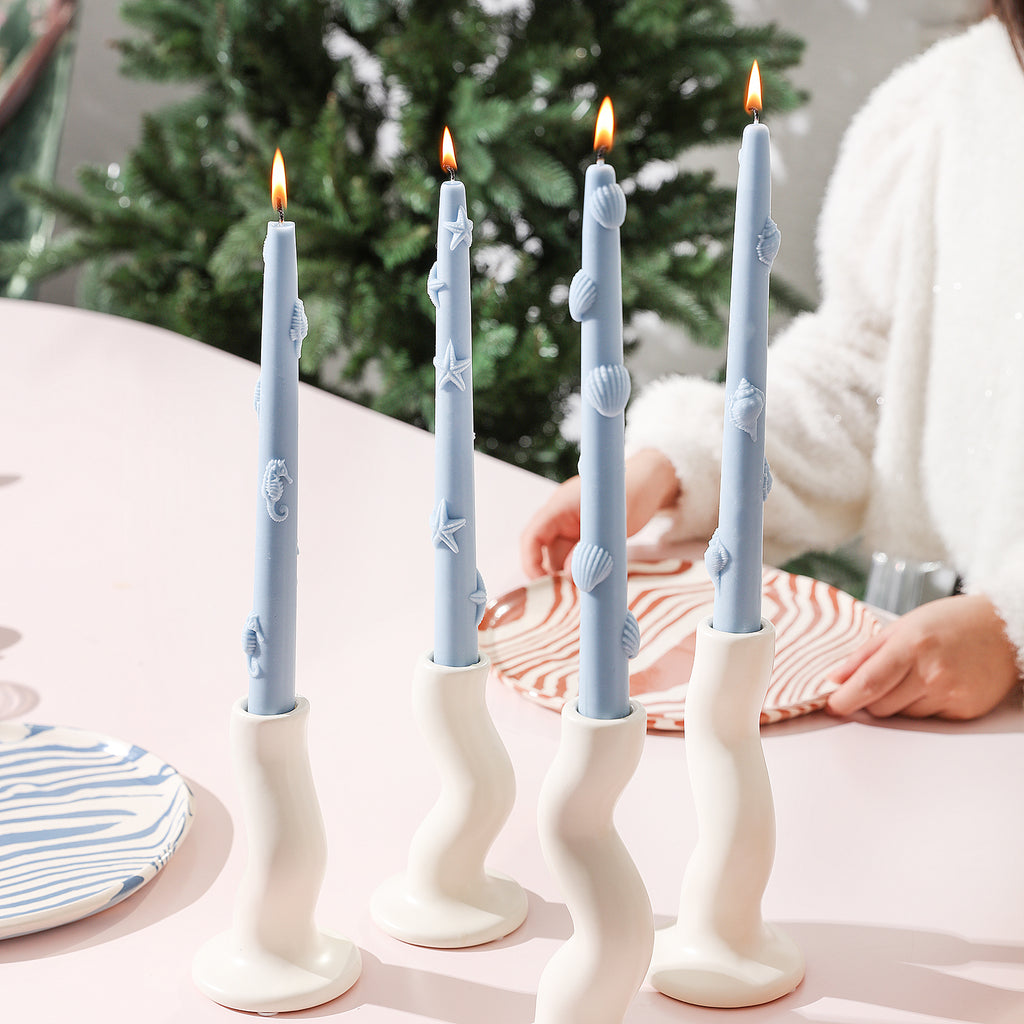Four styles of lit Blue Ocean Collection taper candles.