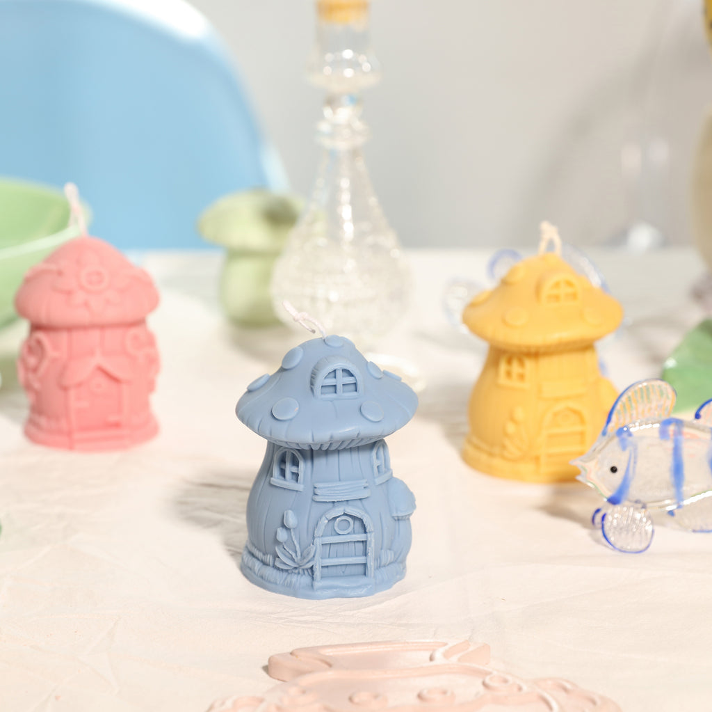 Blue, pink and yellow miniature mushroom house candles on tabletop -Boowan Nicole