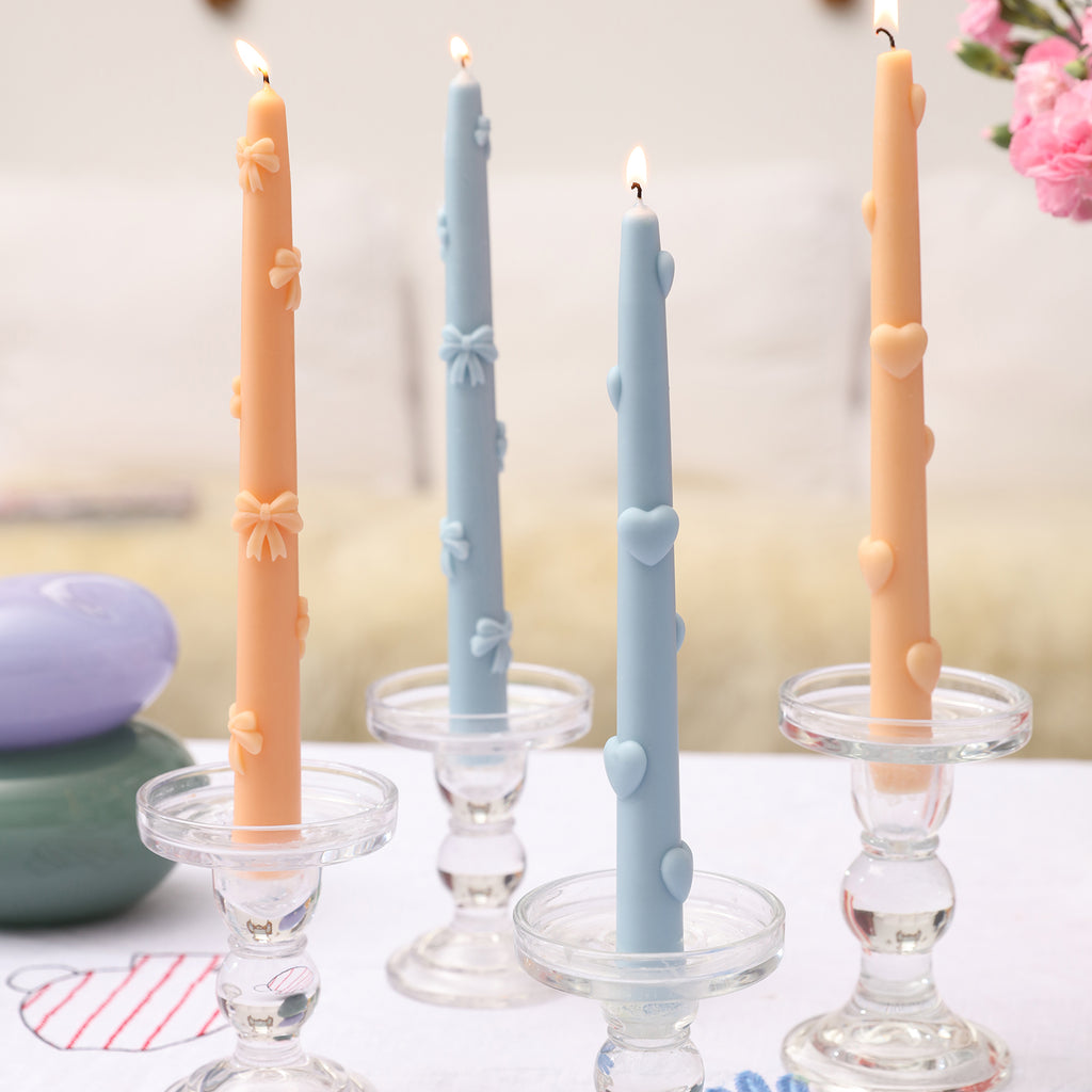 Witness the beauty of four burning Ribbon Bow Taper Candles individually placed on glass candle holders, casting a mesmerizing glow.