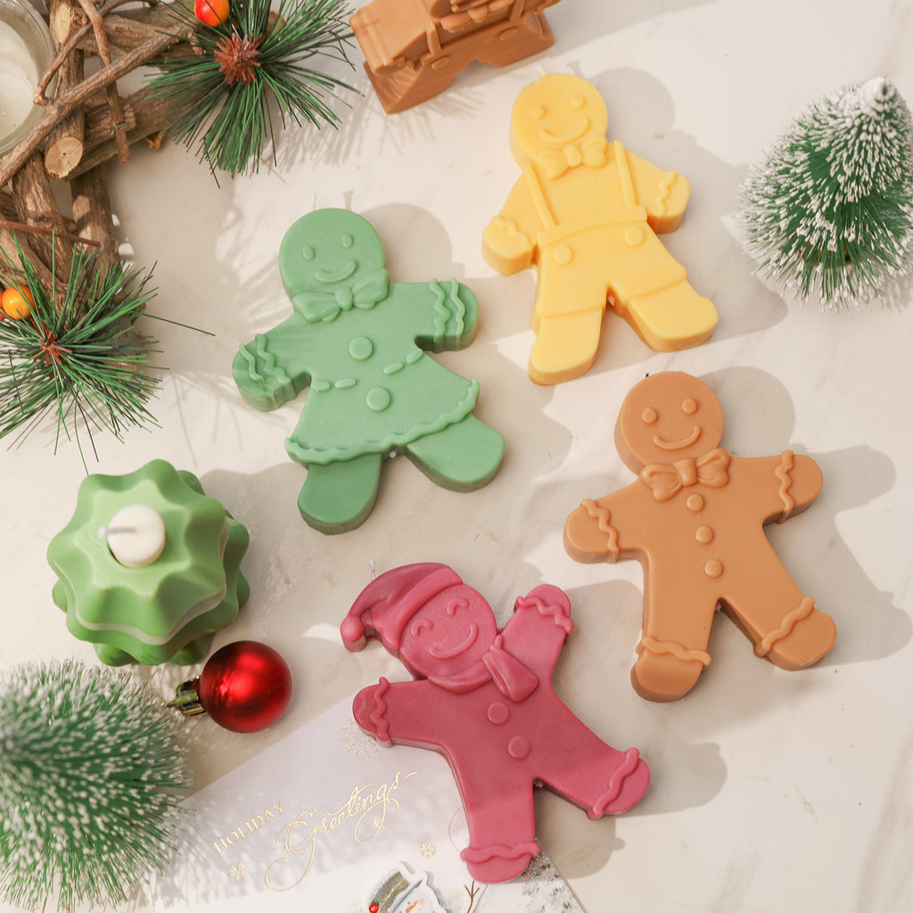 Four Gingerbread Candles of different shapes and colors are placed on the table-Boowan Nicole