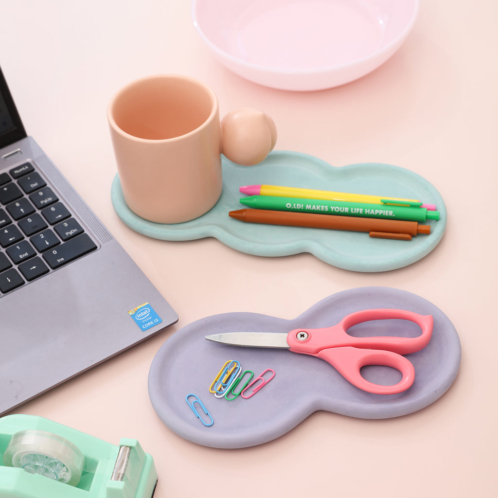 Next to the laptop are scissors in the blue Triple-Nut Peanut-Shaped Tray, and cups and pens in the pink tray - Boowan Nicole