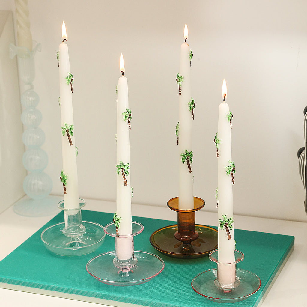 Four painted palm tree embossed taper candles burn slowly in crystal candle holders, adding to the warm atmosphere.
