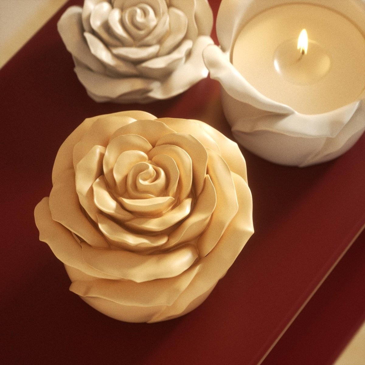 Cream yellow rose-shaped candle jar with a lit white candle, placed on a red tabletop for a soft and warm atmosphere - Boowan Nicole