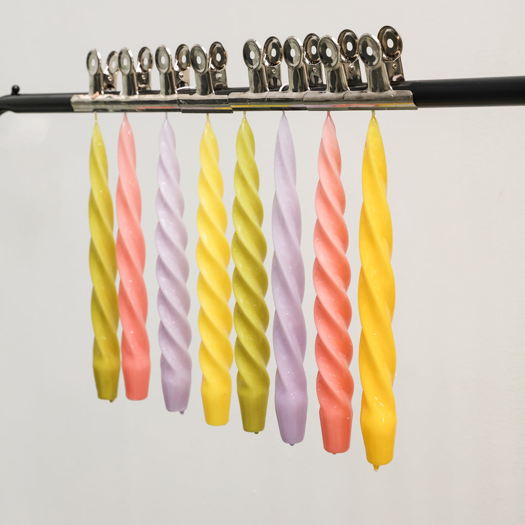 Spiral taper candles crafted with Boowannicole silicone molds, suspended gracefully on a rod.