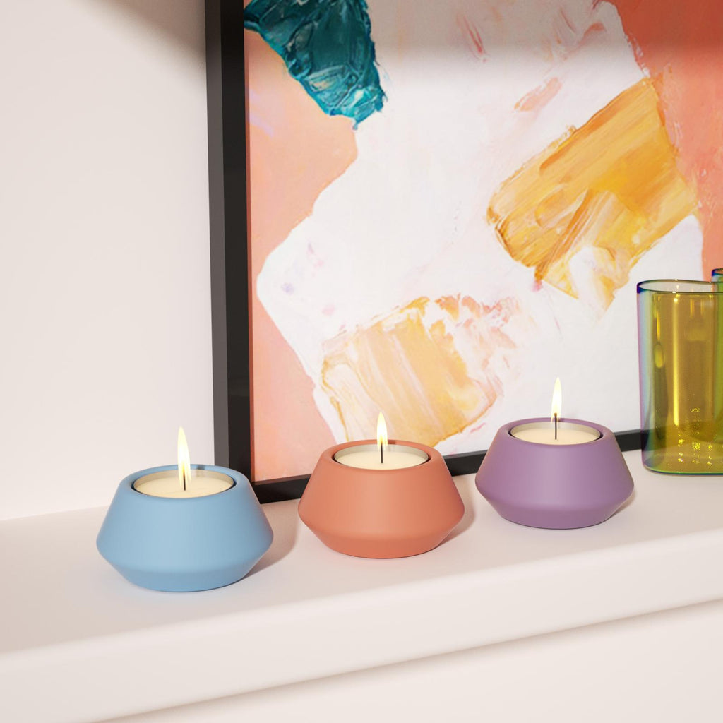 Three lit tealight holders placed on the fireplace, shimmering.