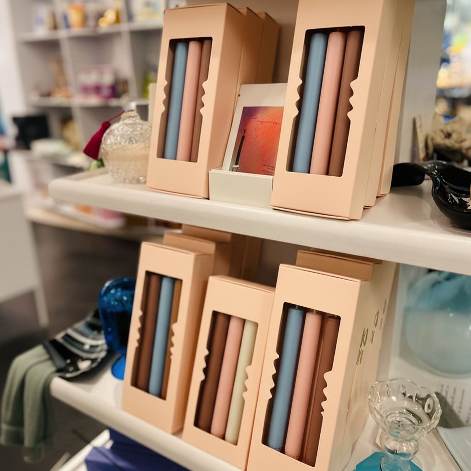 Retail display of gift-boxed 9.3" classic taper candles—peach window boxes showing pairs in pastel blue, blush, cream, and terracotta - Boowan Nicole