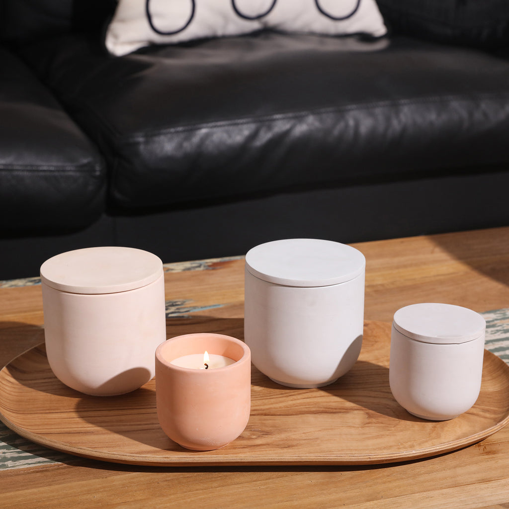 Two large and two small candle jars with flat lids are placed on the tray in the coffee table