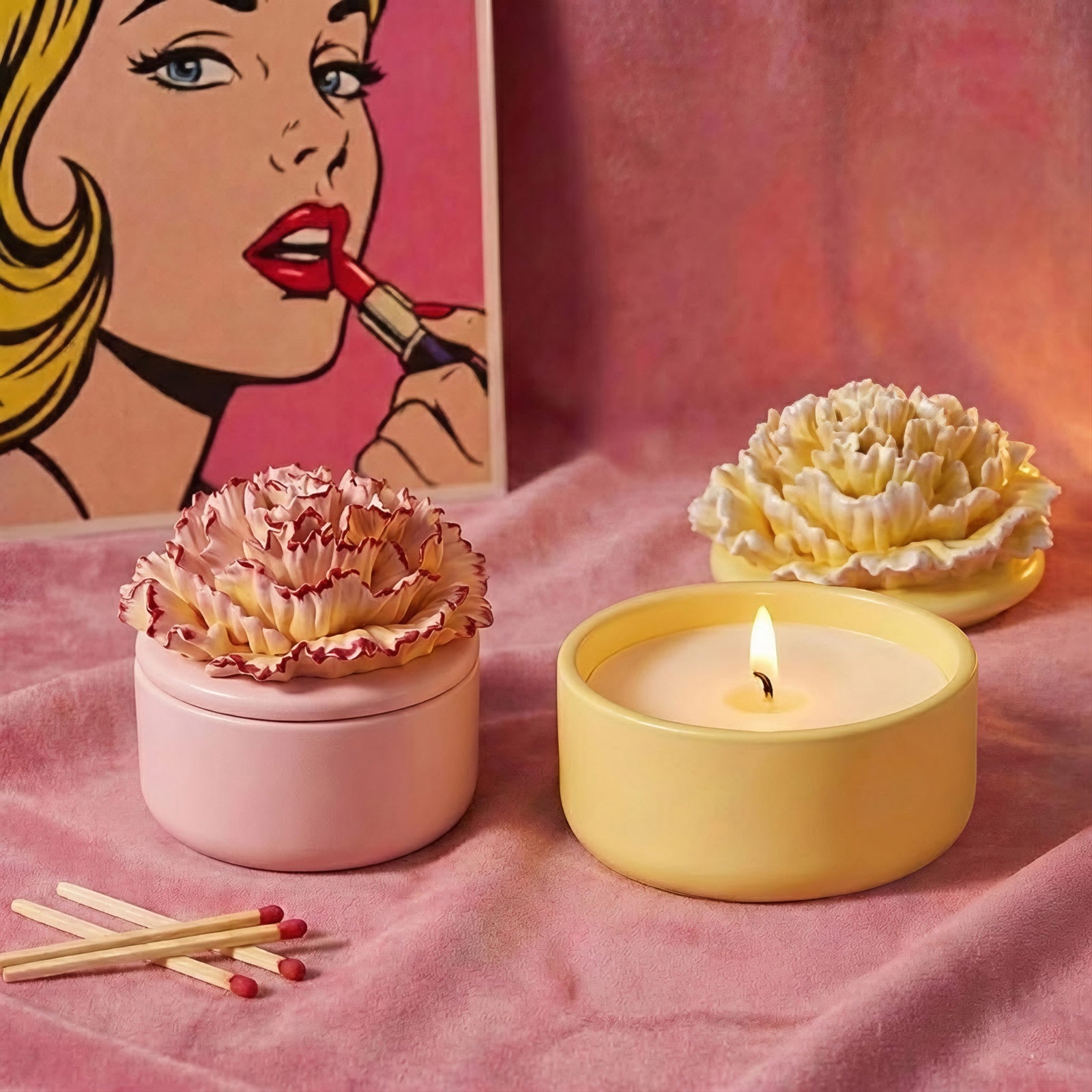 Pink and yellow carnation candle jars with a lit candle on a pink velvet background -Boowan Nicole