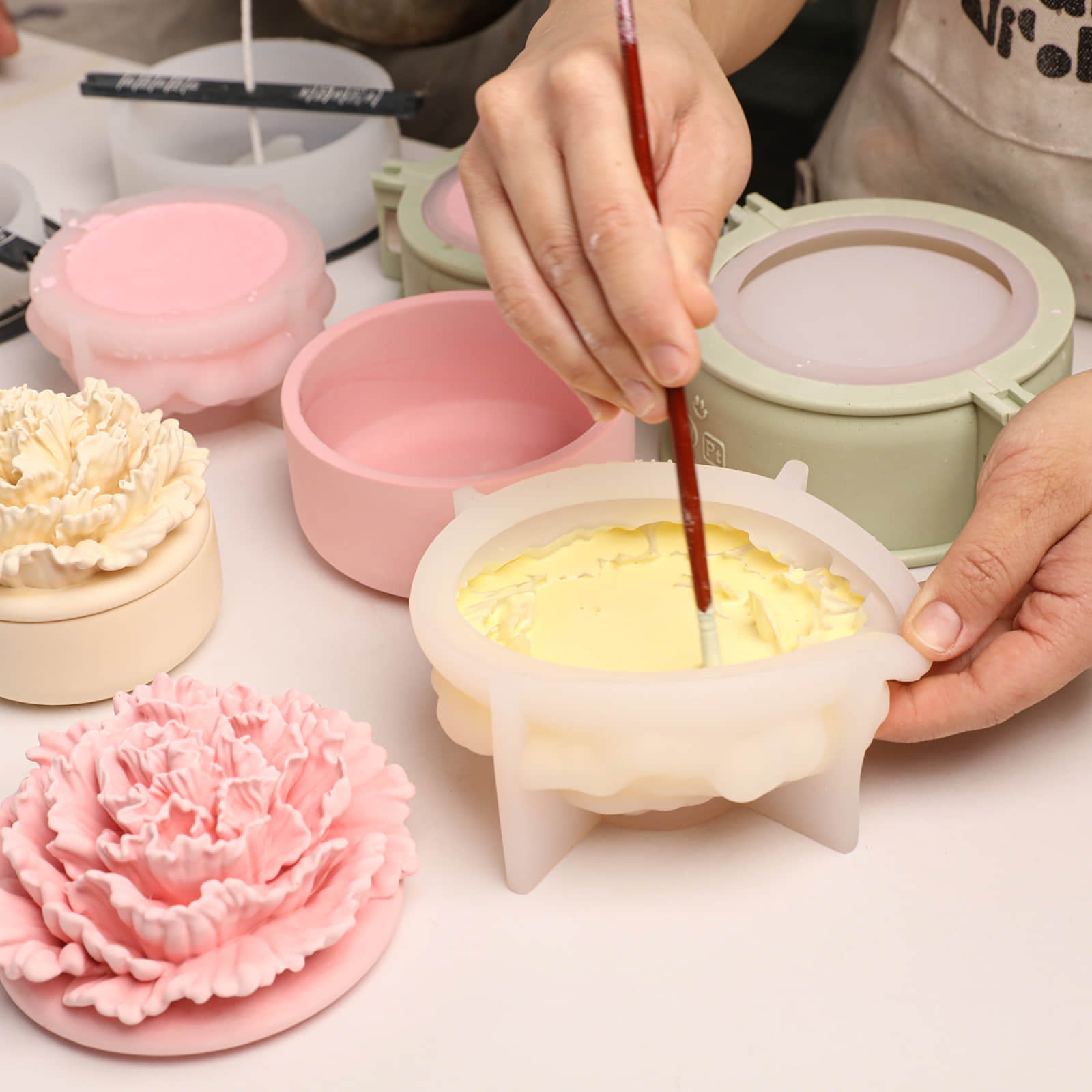 Crafting process: brushing yellow material into a carnation candle jar mold -Boowan Nicole