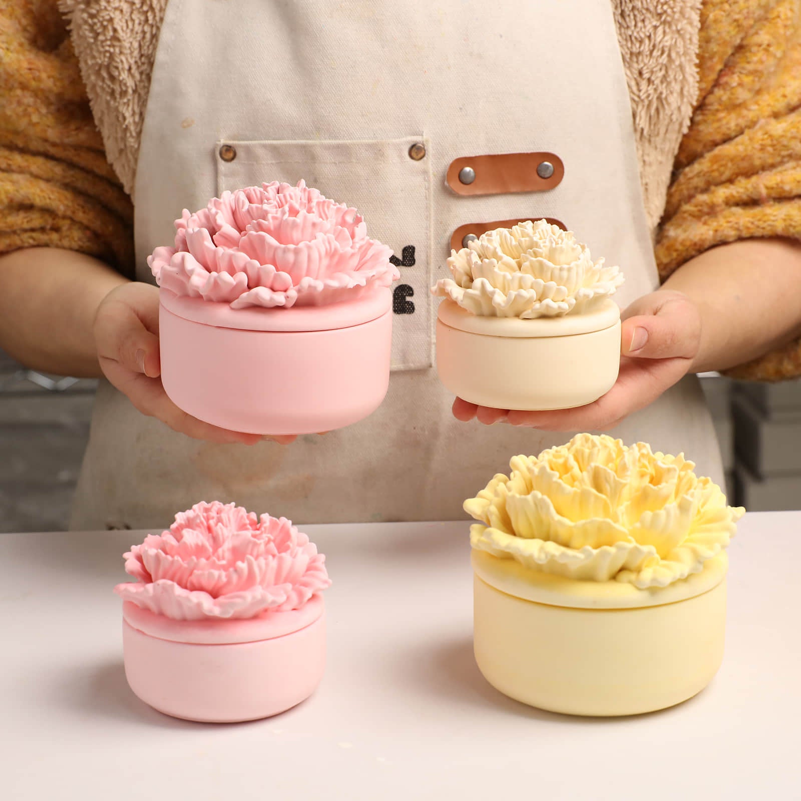 Artisan holding small and large pink and yellow carnation candle jars -Boowan Nicole