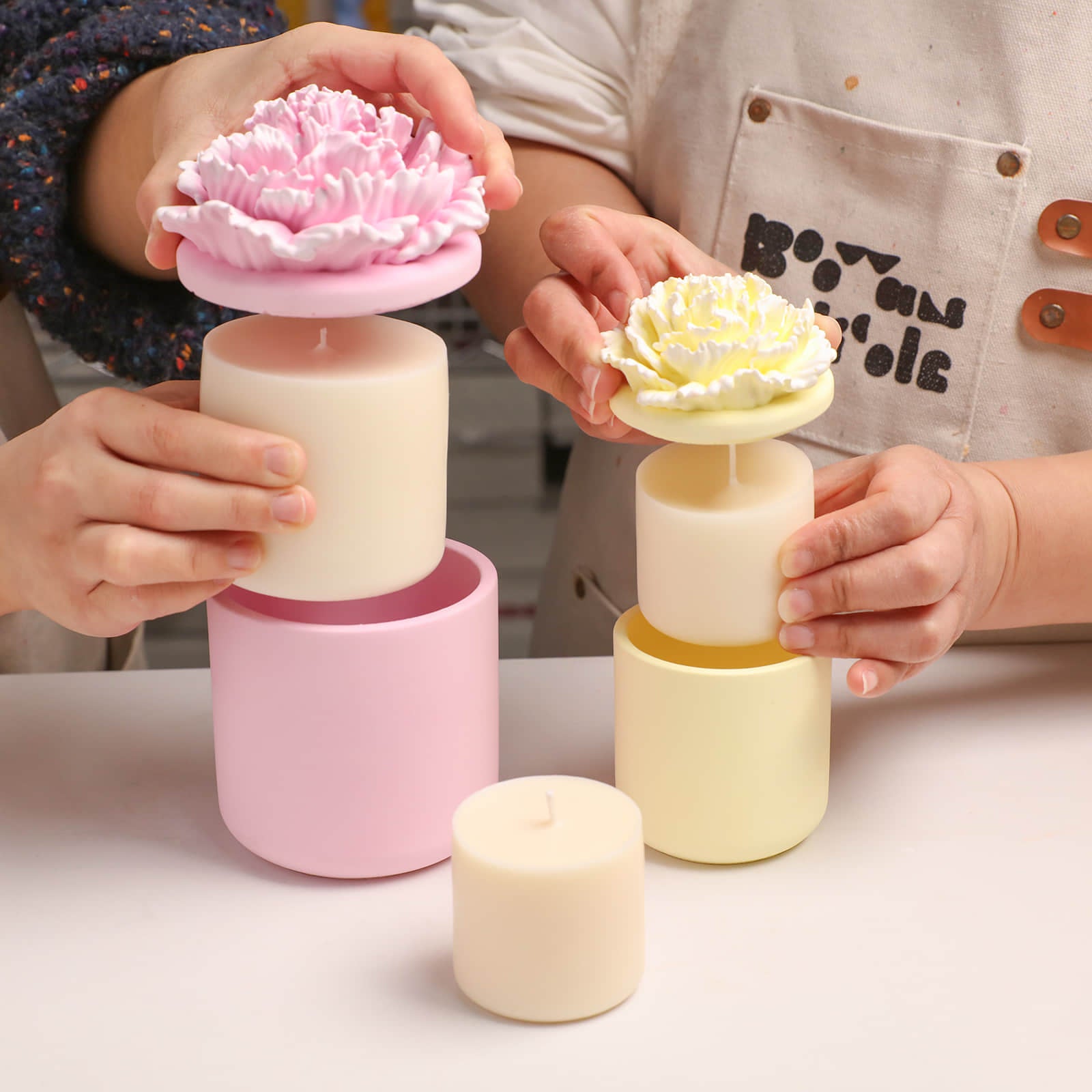 Demonstrating the refillable design of pink and yellow carnation candle jars -Boowan Nicole