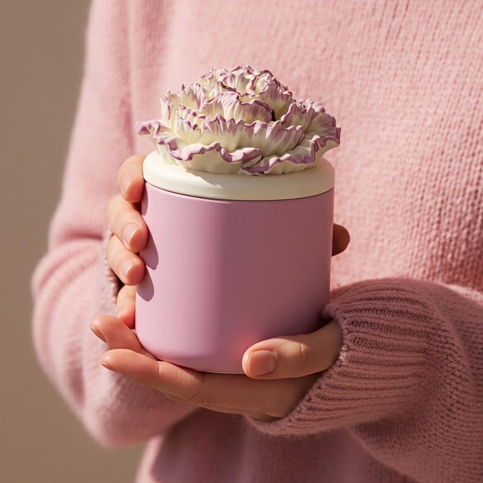 Holding a purple-edged carnation candle jar in a pink knit sweater -Boowan Nicole