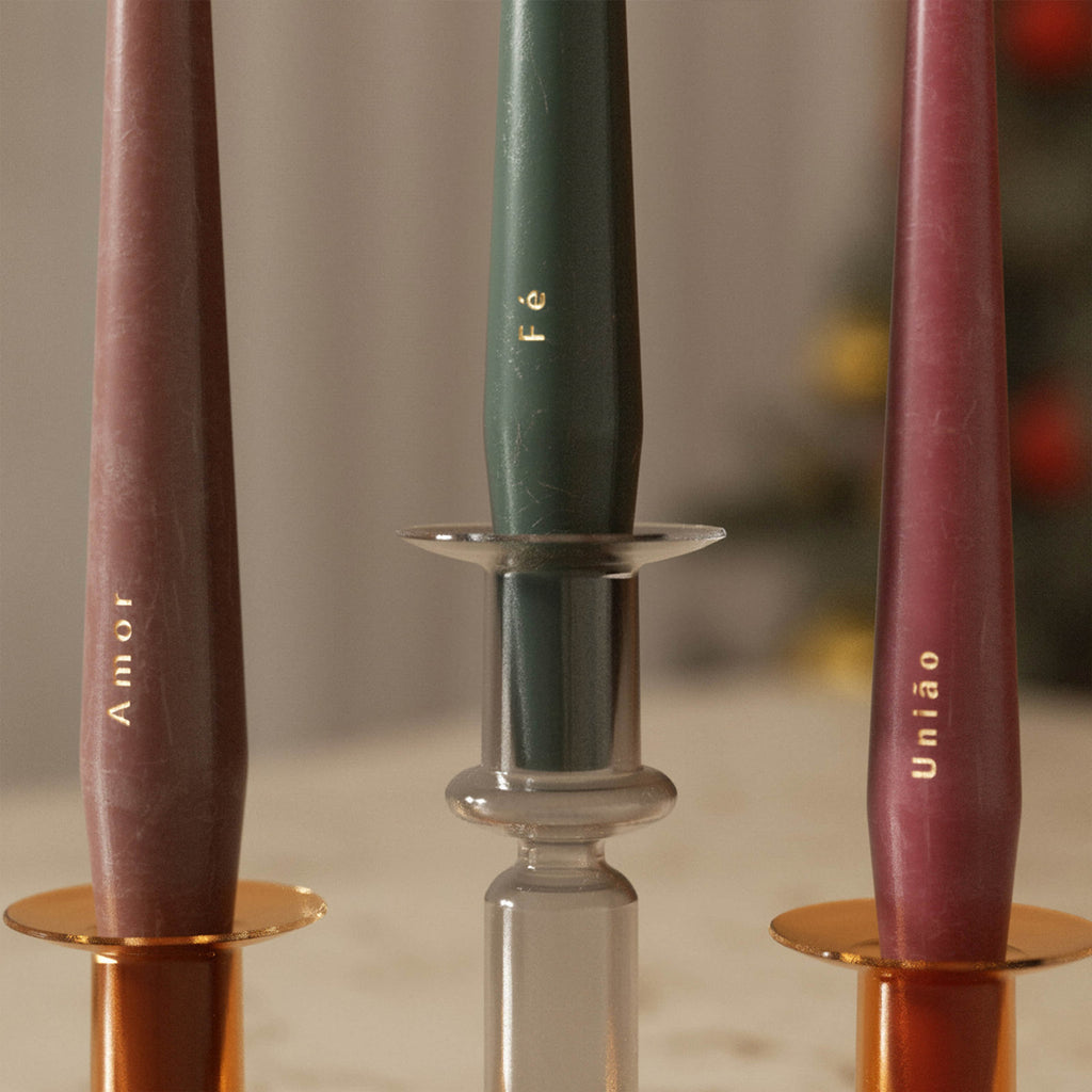 Close-up of three taper candles in glass holders—burgundy “Amor,” green “Fé,” and berry “União” - Boowan Nicole