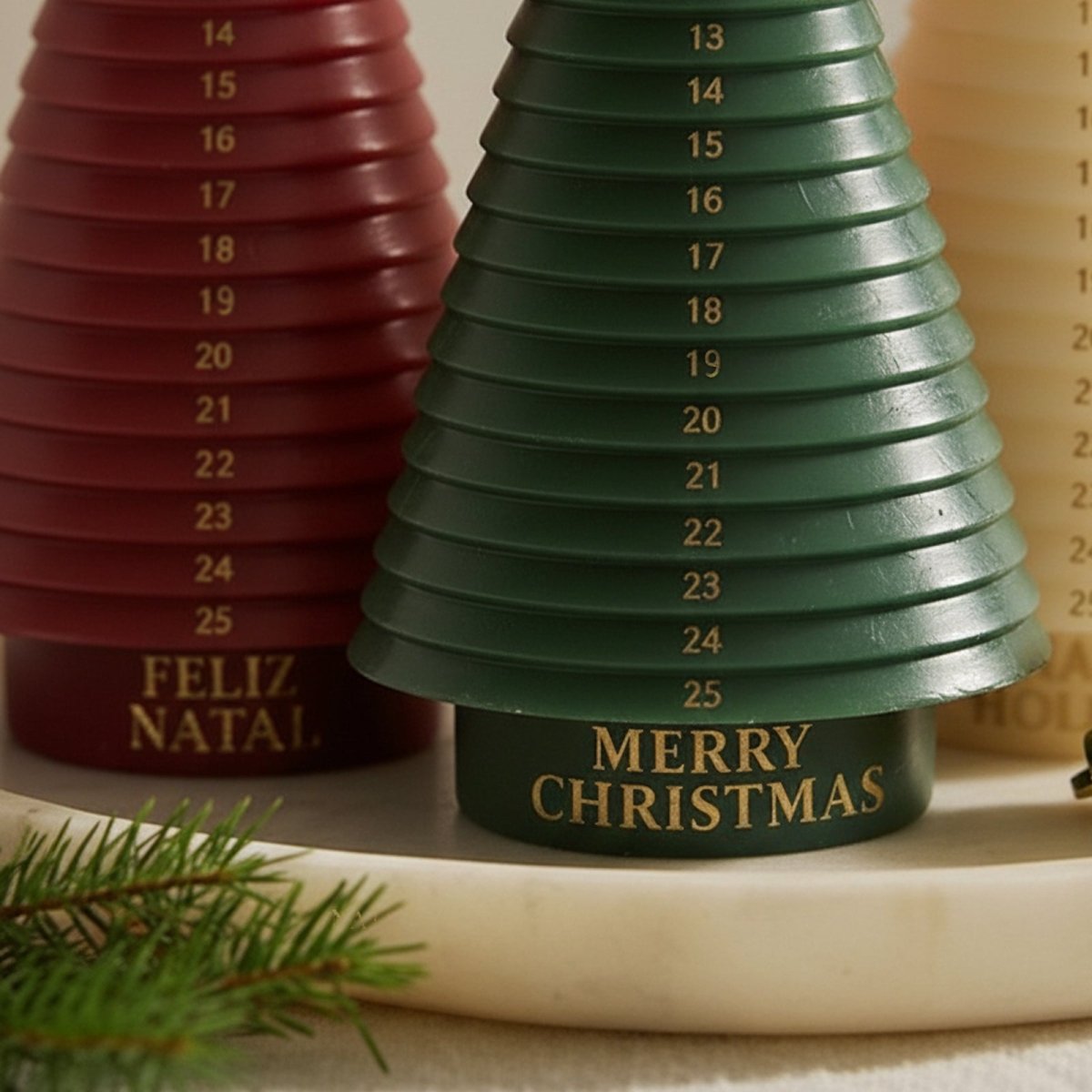 Close-up of green advent tree candle—“Merry Christmas” with gold numbers; red “Feliz Natal” behind - Boowan Nicole