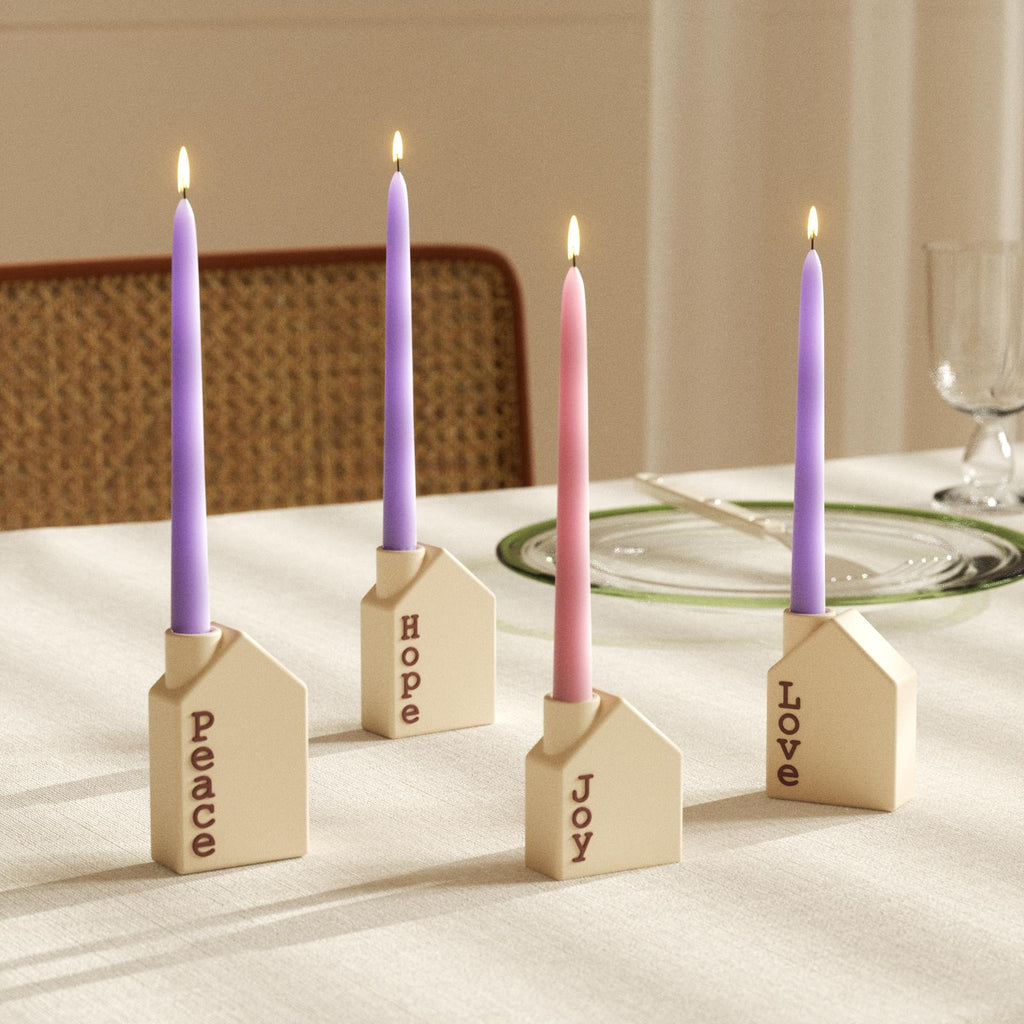 Advent taper candles in house-shaped holders labeled Peace, Hope, Joy, and Love on dining table - Boowan Nicole