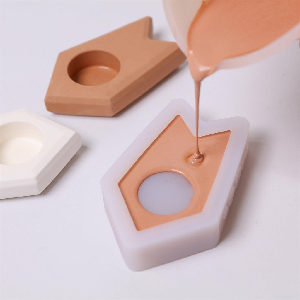 Pouring mixed concrete into a house-shaped silicone mold for DIY candle holder making - Boowan Nicole