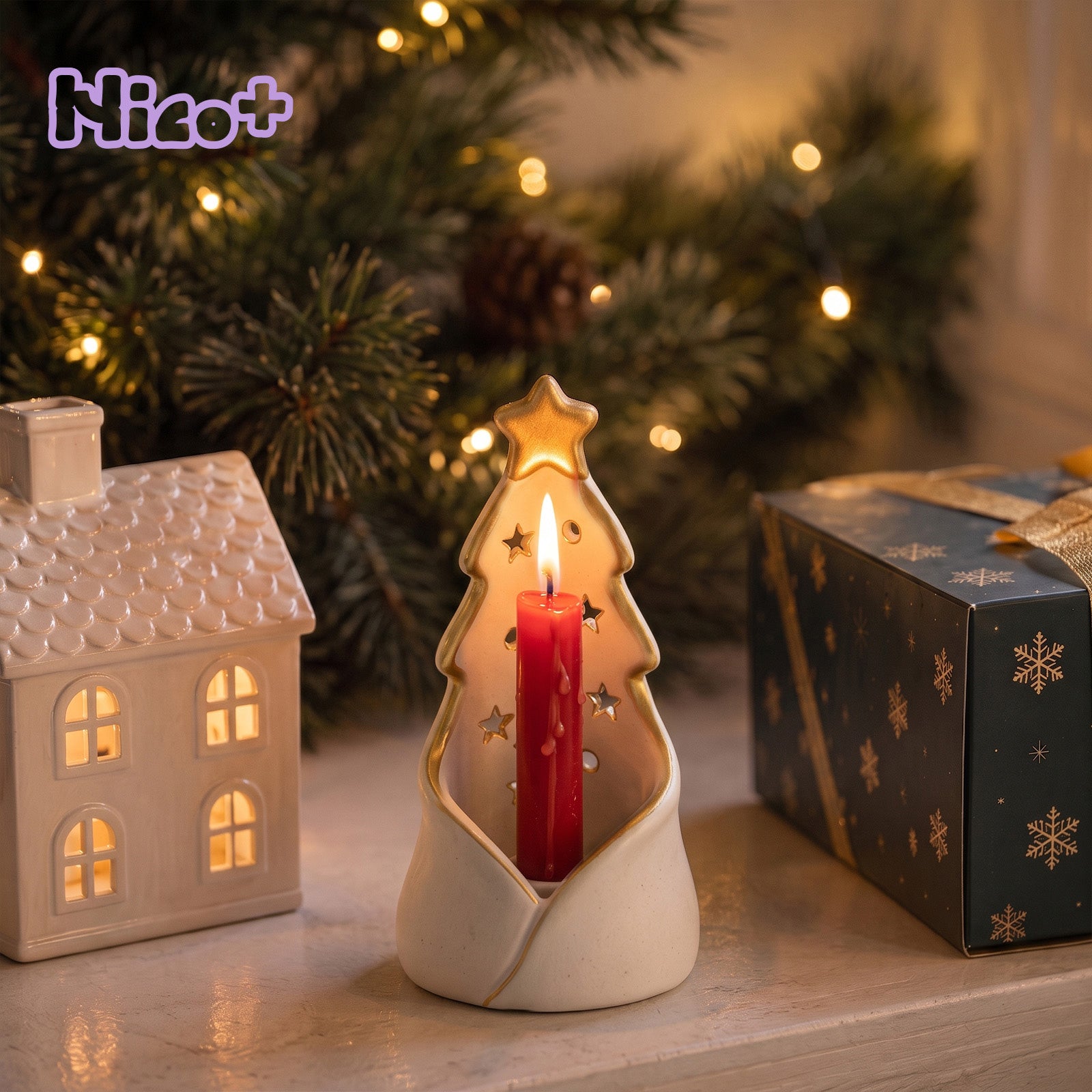 A ceramic Christmas tree-shaped candle holder with a lit red taper candle, styled on a tabletop with a miniature house, a wrapped gift, and blurred Christmas tree lights in the background. The brand name 'Nicoo+' appears in the top left corner.