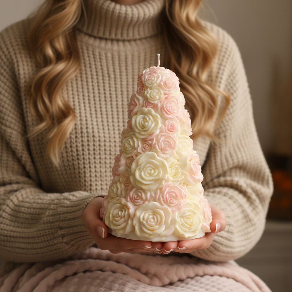 Hands in a cozy sweater holding a large pastel pink and cream rose tree candle - Boowan Nicole