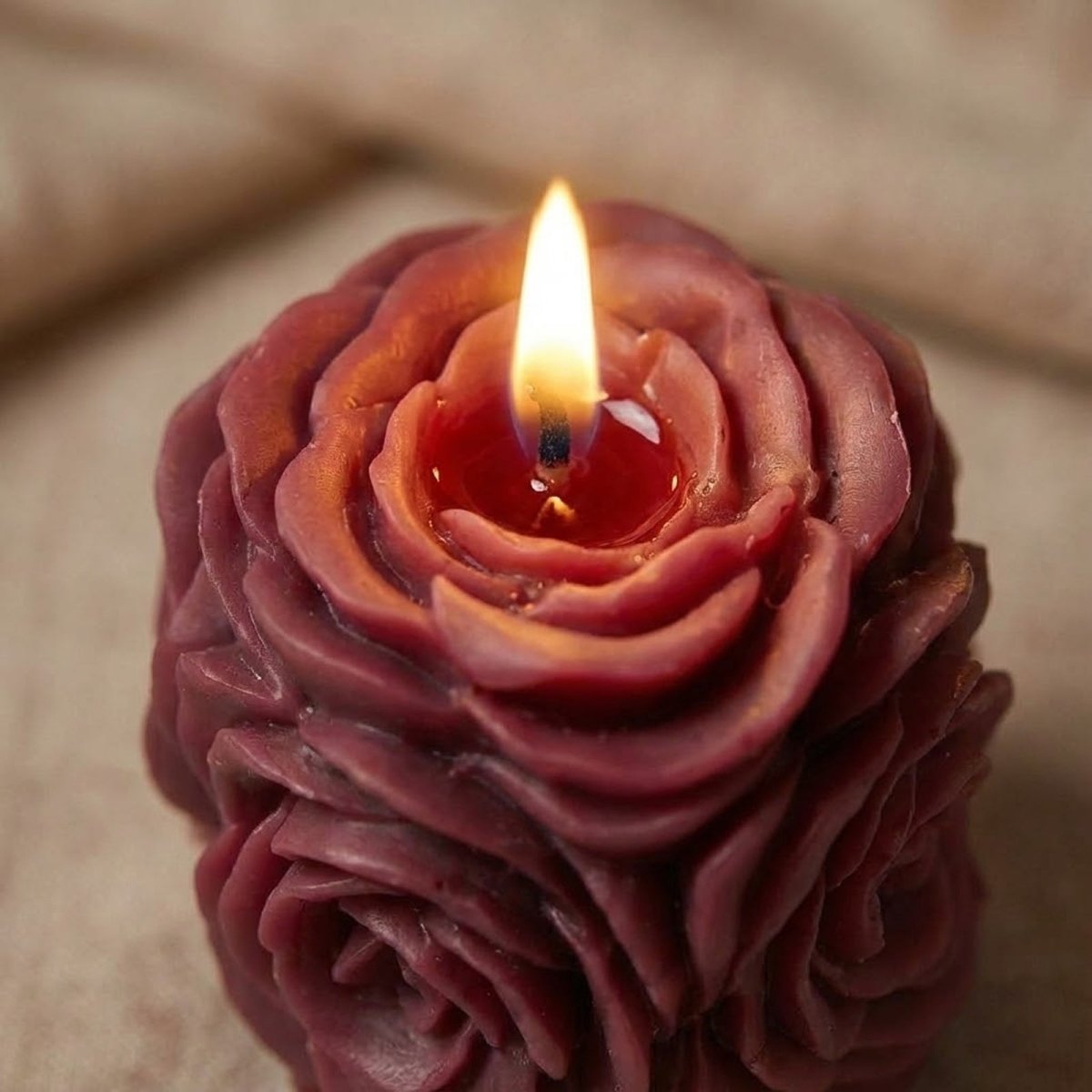 Lit rose pillar candle with soft flame and detailed floral petals. - Boowan Nicole