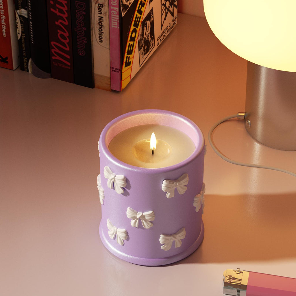 Purple bowknot candle jar with mica shimmer, made using Boowan Nicole silicone mold, placed on a cozy desk by a lamp and books-Boowan Nicole