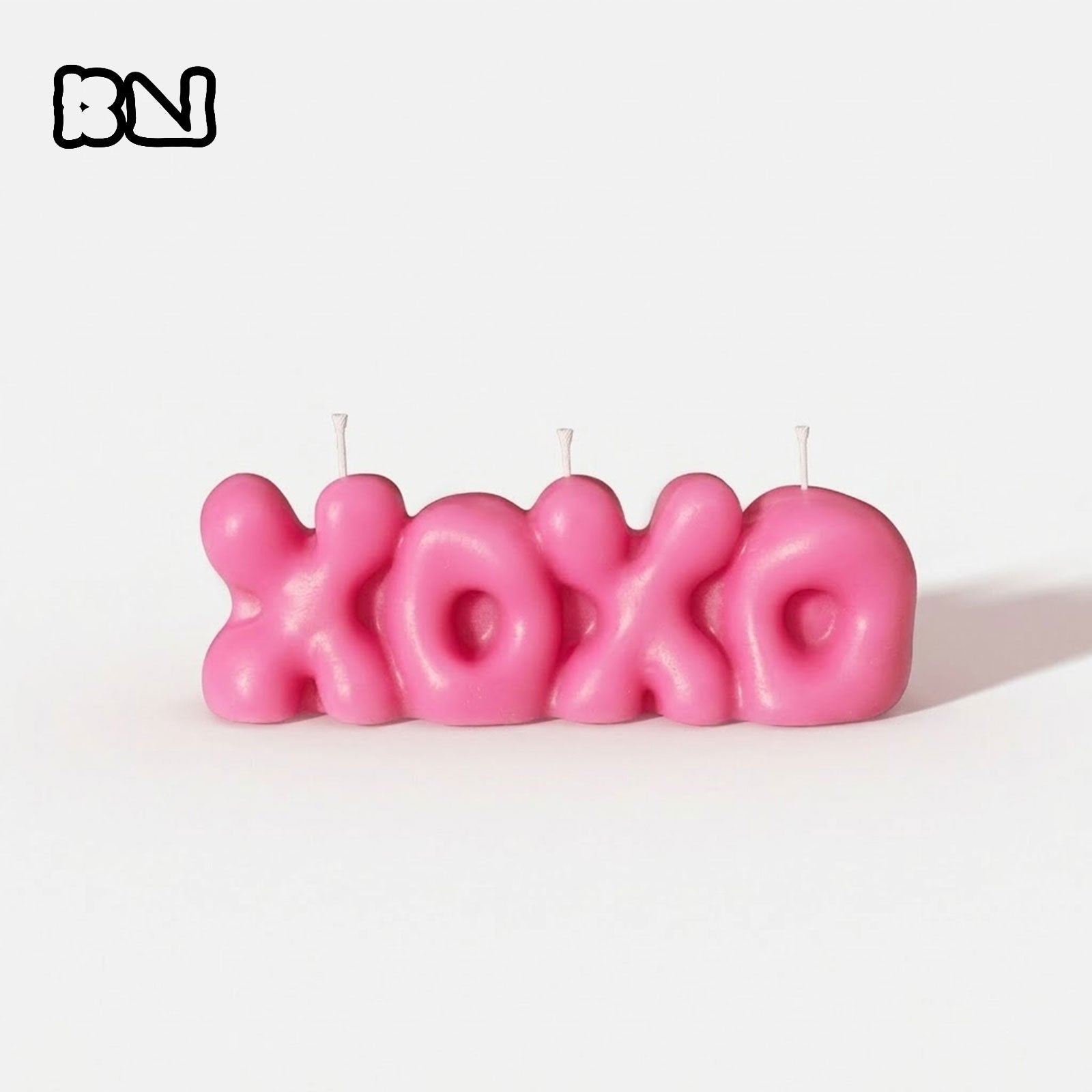 Bright pink bubble-shaped "XOXO" letter candle with BN logo, displayed against a white background. -Boowan Nicole