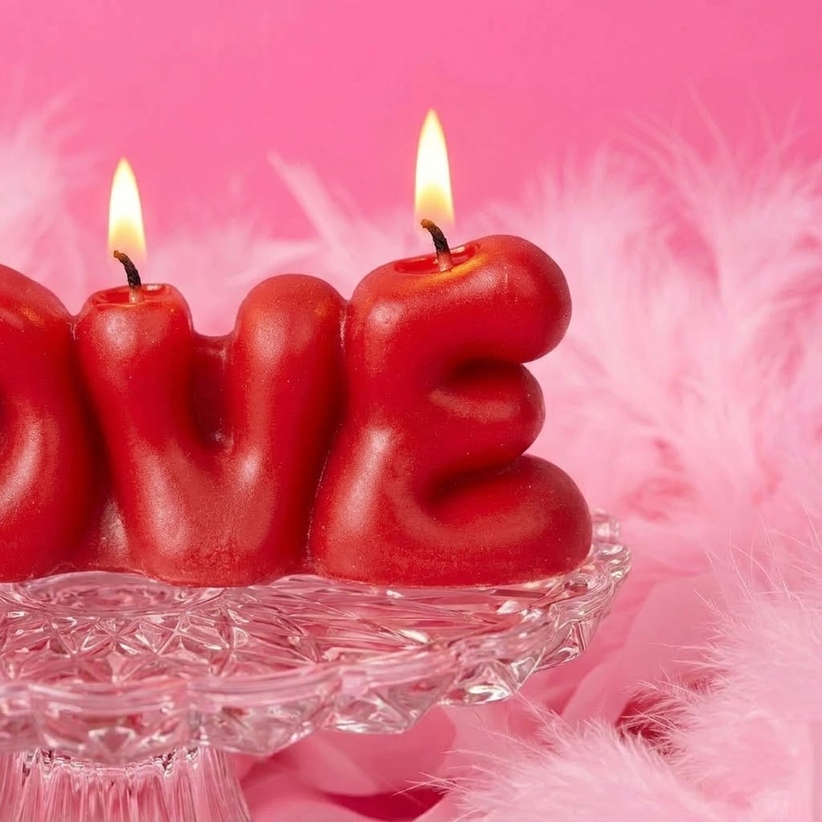 Close-up of a lit red "LOVE" bubble letter candle, showing melting wax and warm flame. -Boowan Nicole