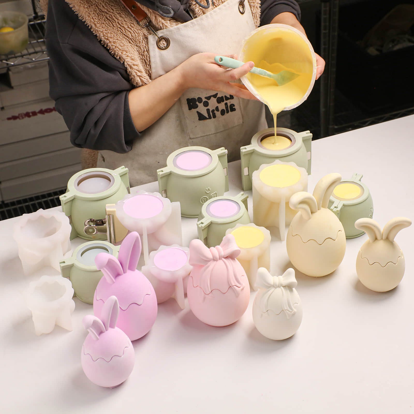 Pouring material into silicone molds to create pastel bunny ear egg-shaped candle jars -Boowan Nicole