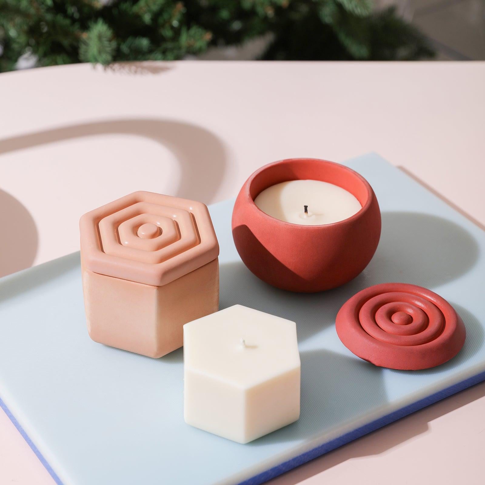 Polygonal and oval candle jars are placed on trays, along with refill candles.