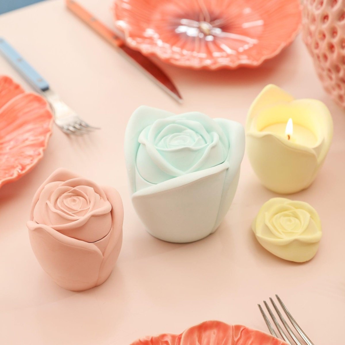 The yellow, pink, and cyan Rose Reverie Candle Jar is placed on the table, and the candles in the yellow candle jar are burning slowly-Boowan Nicole