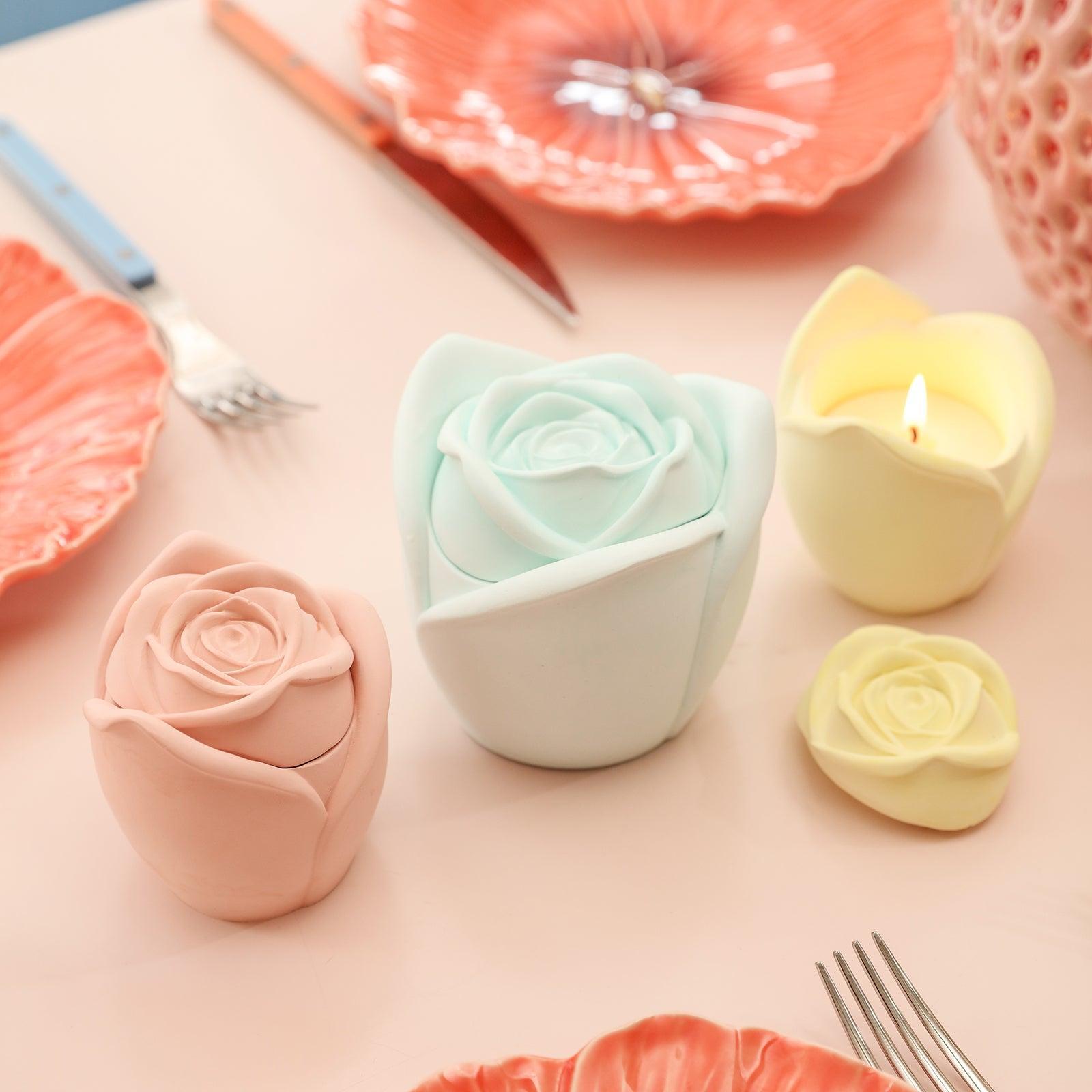 The yellow, pink, and cyan Rose Reverie Candle Jar is placed on the table, and the candles in the yellow candle jar are burning slowly-Boowan Nicole