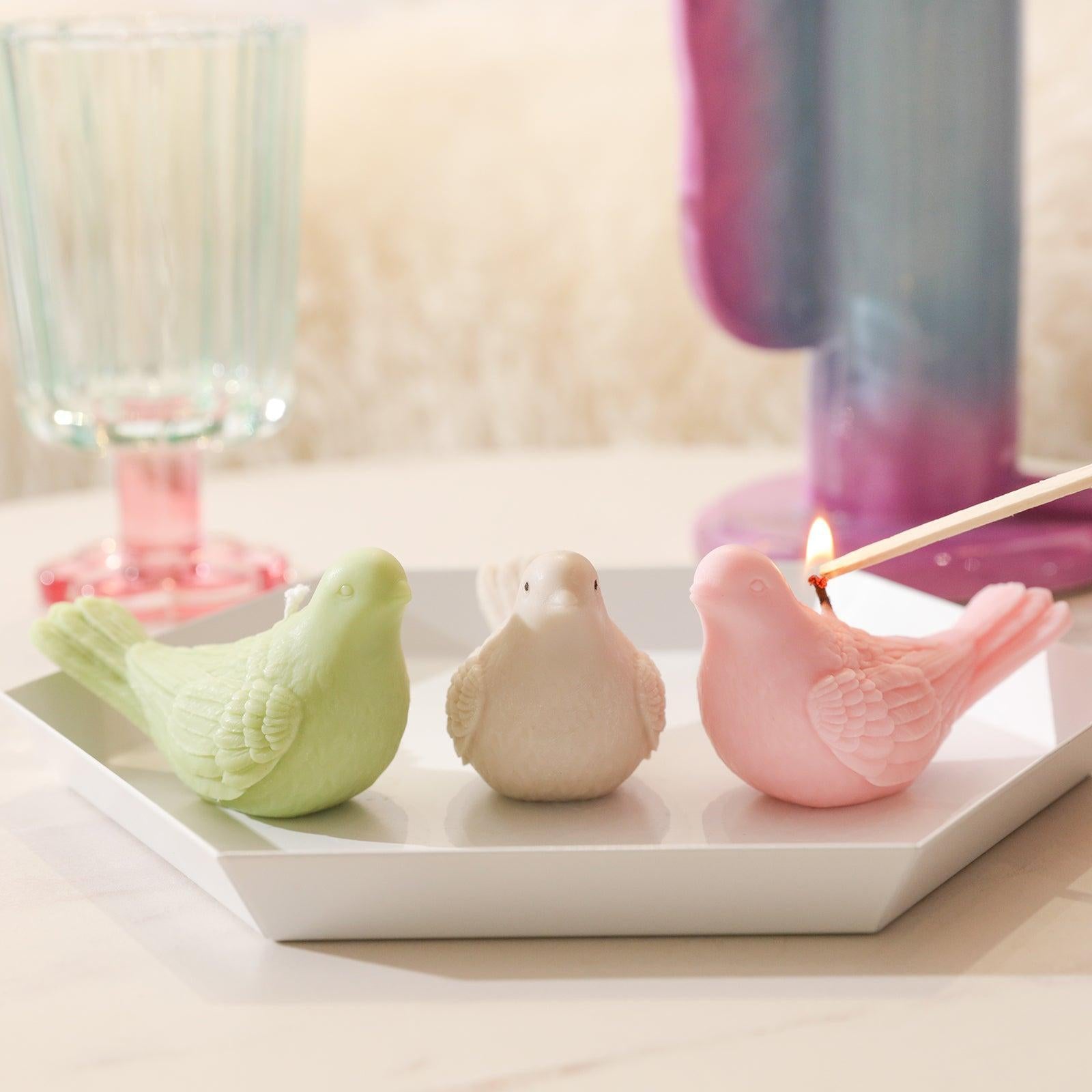 Light the pink dove-shaped tea light candle in the tray, designed by Boowan Nicole.